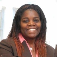 Mary Otiato, a smiling, confident woman wearing a brown blazer